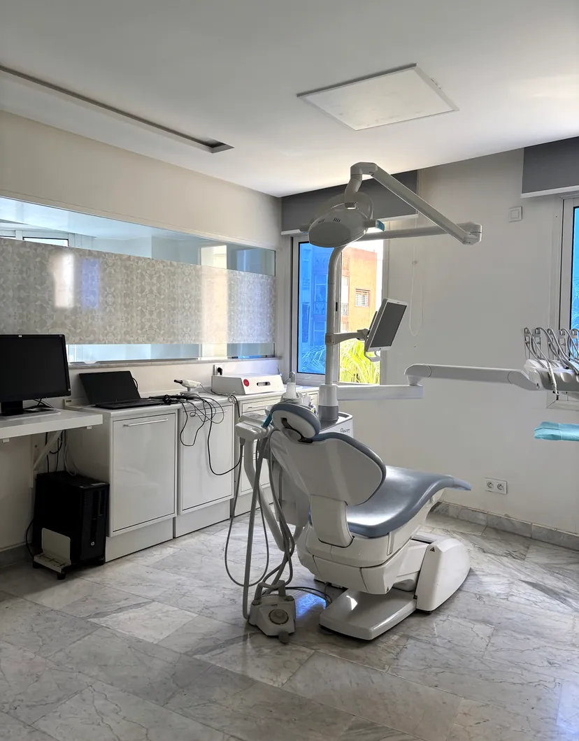 Salle de soins lumineuse avec fauteuil dentaire et fenêtre